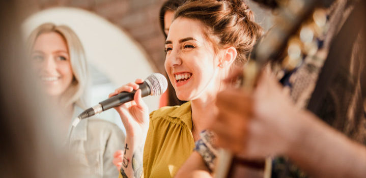 Entertianment at a wedding. A female singer is interacting with the crowd while a man plays an acoustic guitar.